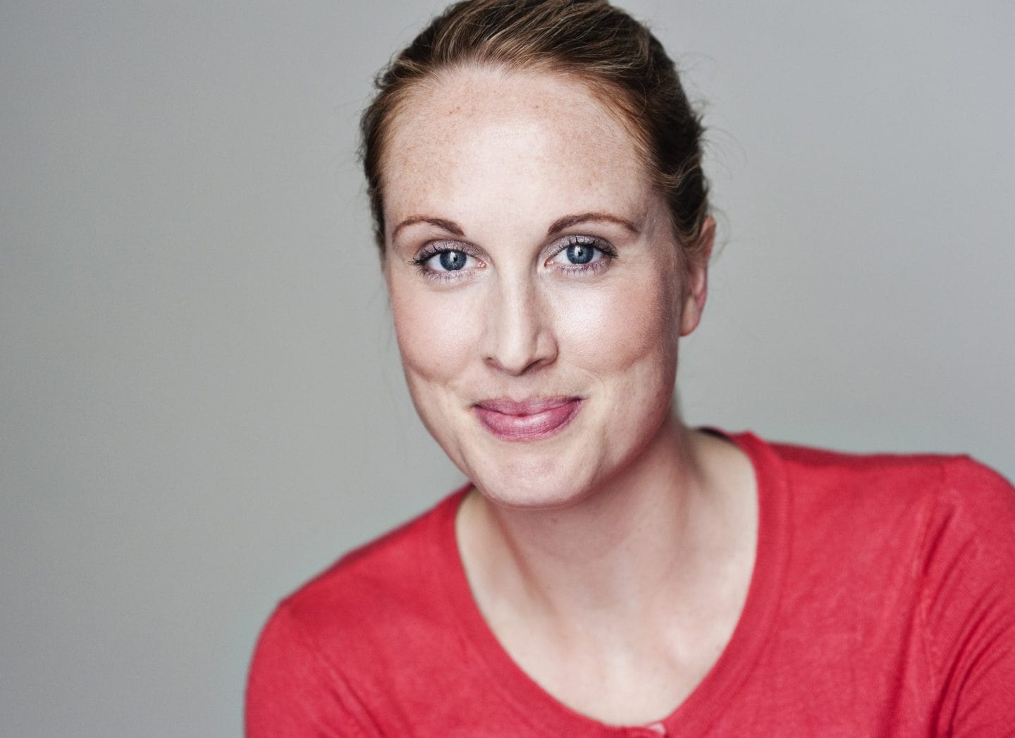 Headshot of Amy Allen in a red shirt with hair brushed back into a ponytail