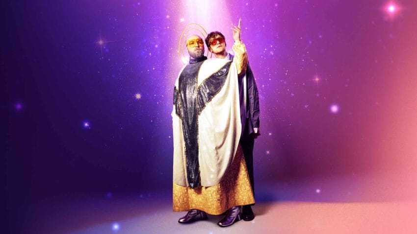 Two people wearing priest's robes stand light coming down from above. The background is purple and sparkling.