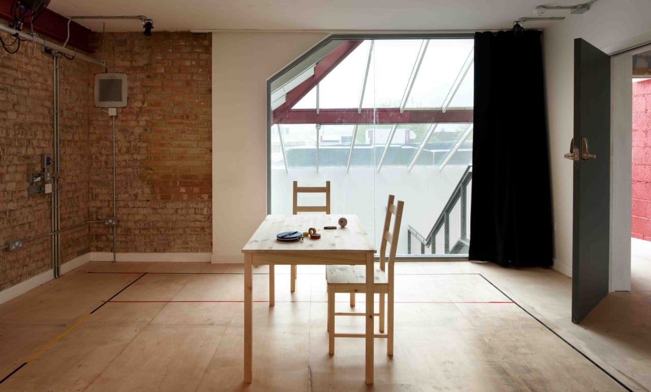 Inside the Morris Space, a large window lights up the space with 2 chairs and table in the middle of the room