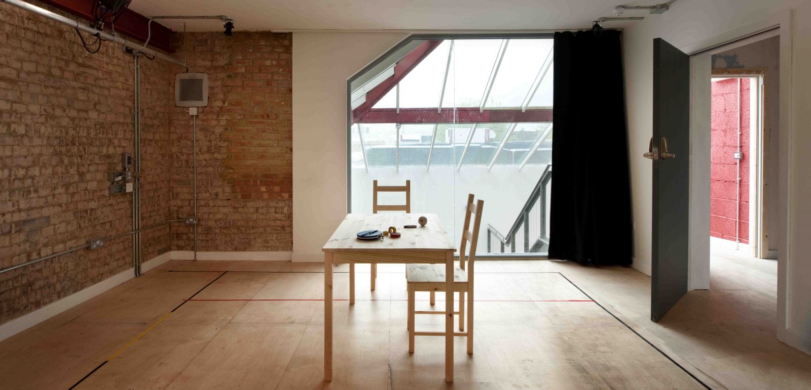 Inside the Morris Space, a large window lights up the space with 2 chairs and table in the middle of the room