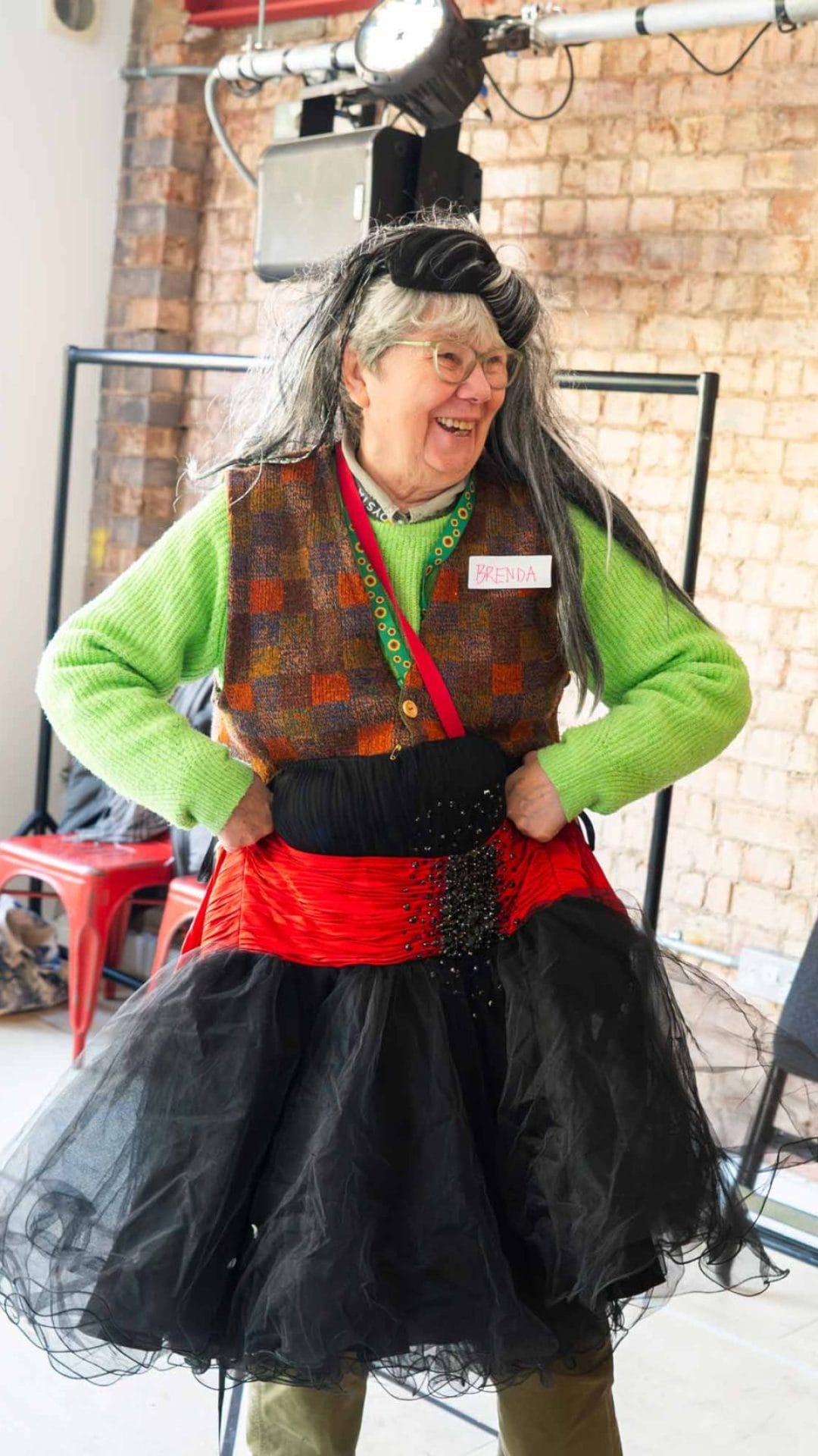 Photo of a woman dressing up with a long wig and a long black and red skirt.