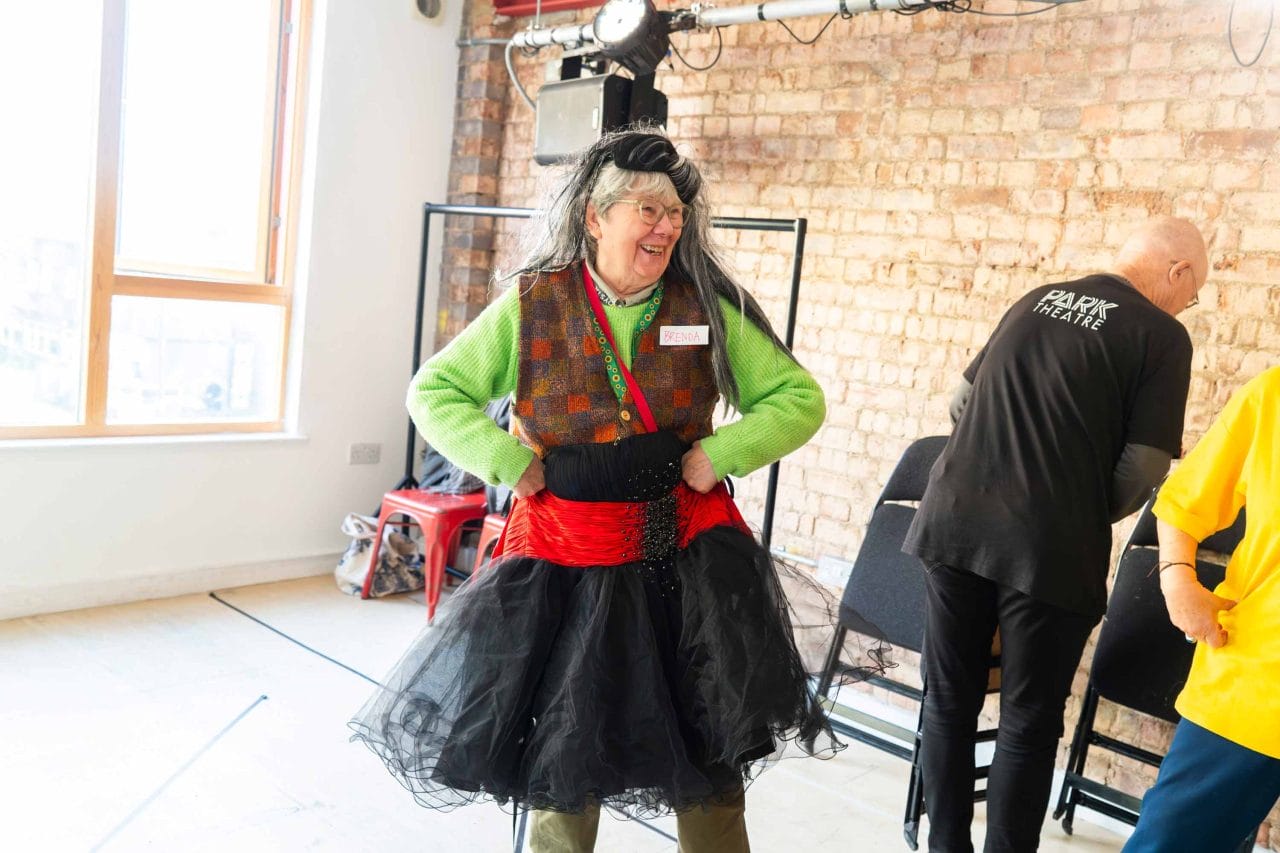 Photo of a woman dressing up with a long wig and a long black and red skirt.