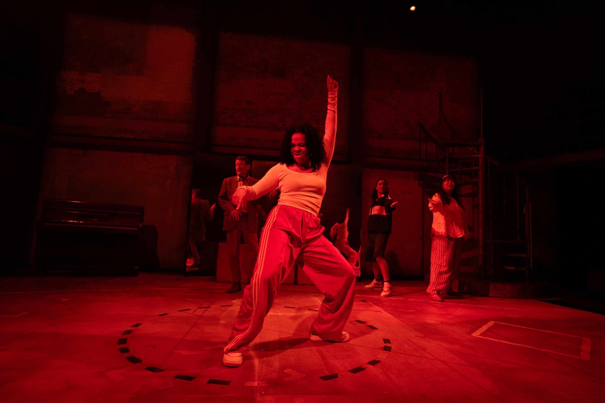 Production shot of a woman standing in the centre and dancing and 3 people dancing behind her