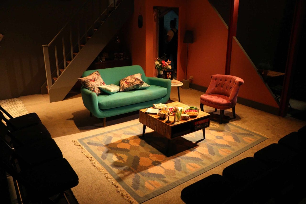 An image of a living room set, a green sofa, small dining table and a red chair