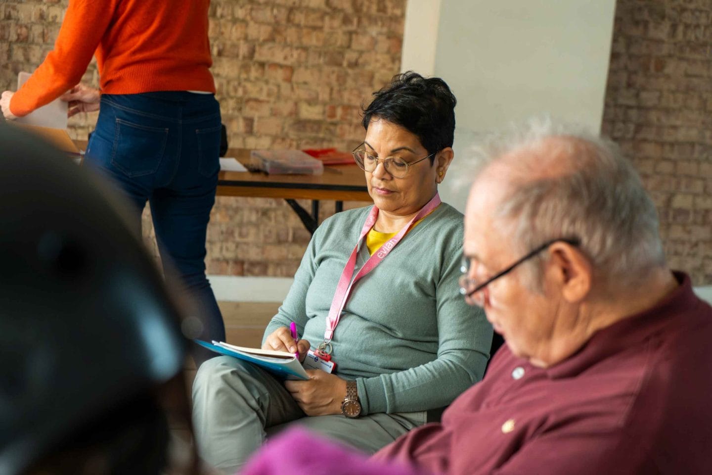 A woman wearing glasses sits next to a man while highlighting a journal