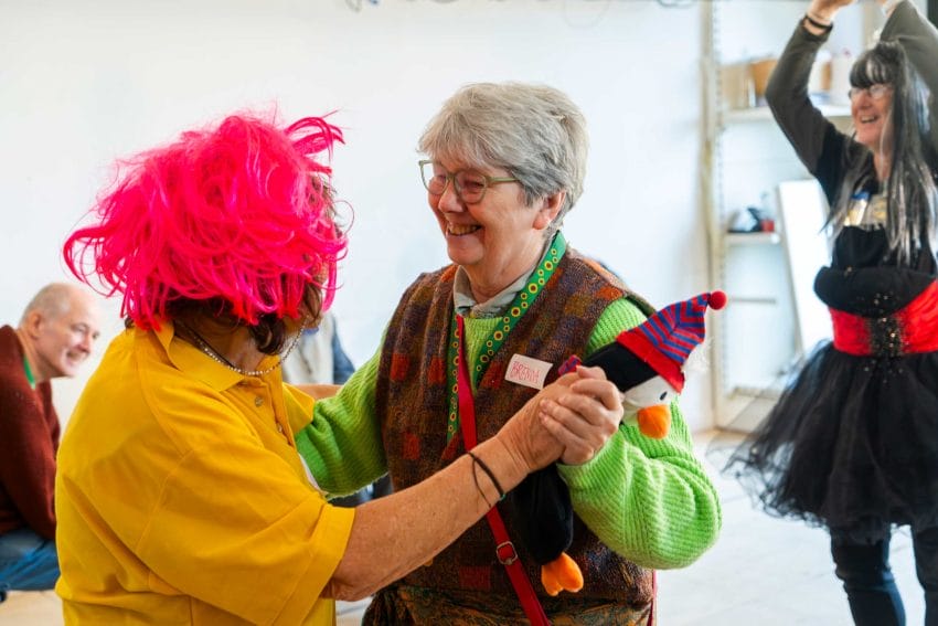 A photo of people dancing together while wearing wigs and costumes.