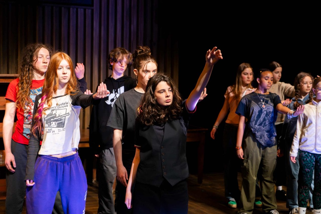 Group of young people on stage in rows with their hands out in front of them