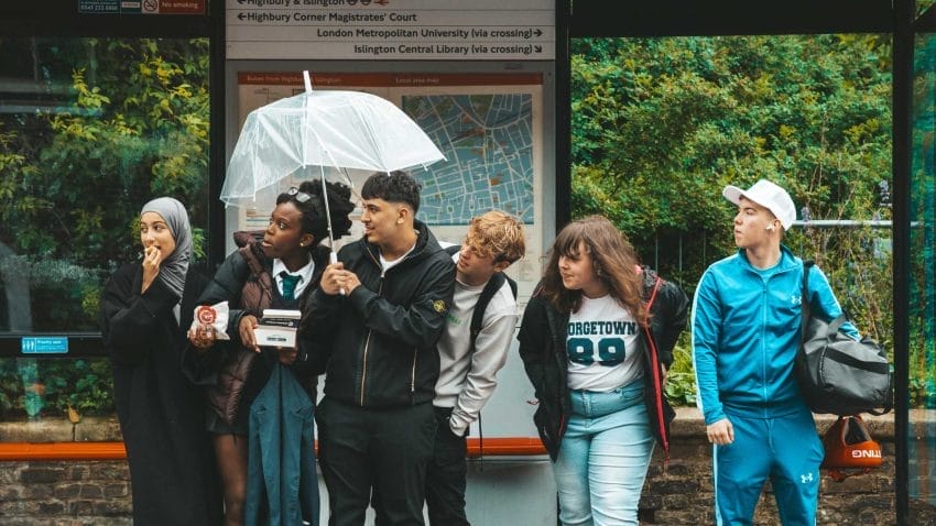 Six young people stand in front of a bus stop.